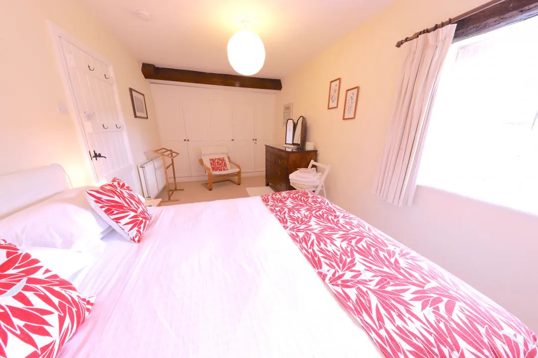 Double bedroom with white and red bed linen and a window to the fells