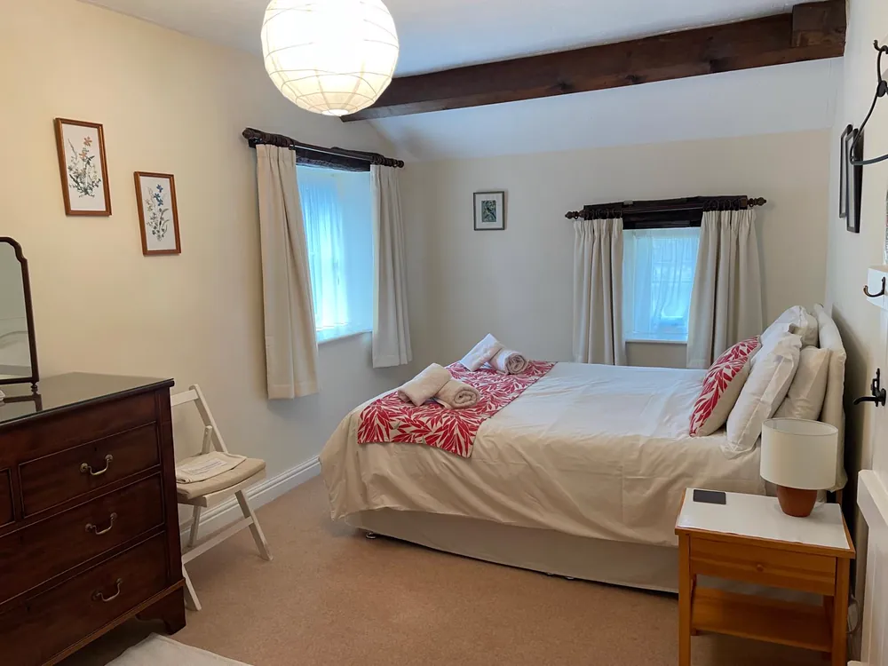 Master bedroom with a king-size bed, chest of drawers and window seat